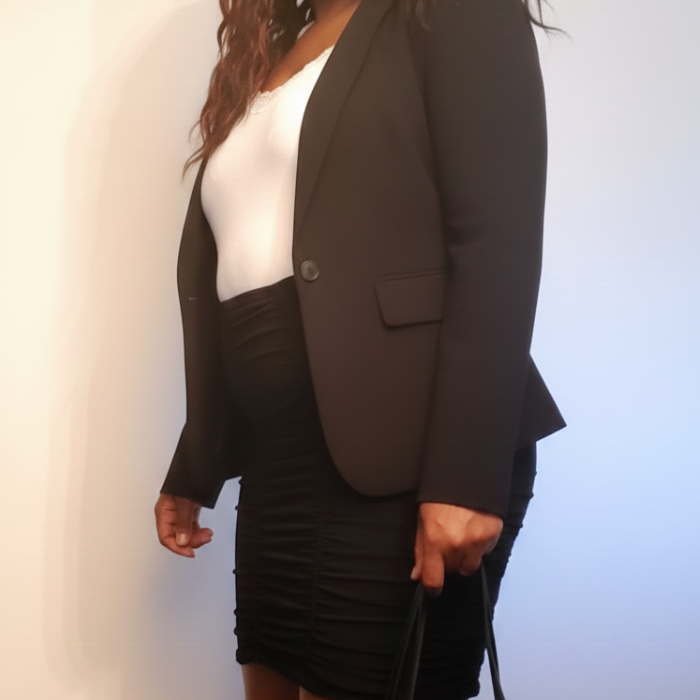 Aisha wearing a black blazer, white cami, and black ruched skirt