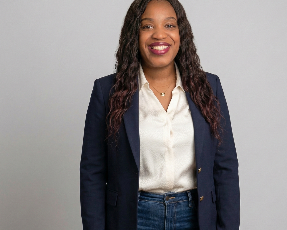 An image of a model wearing a navy blazer, white blouse, and dakr denim
