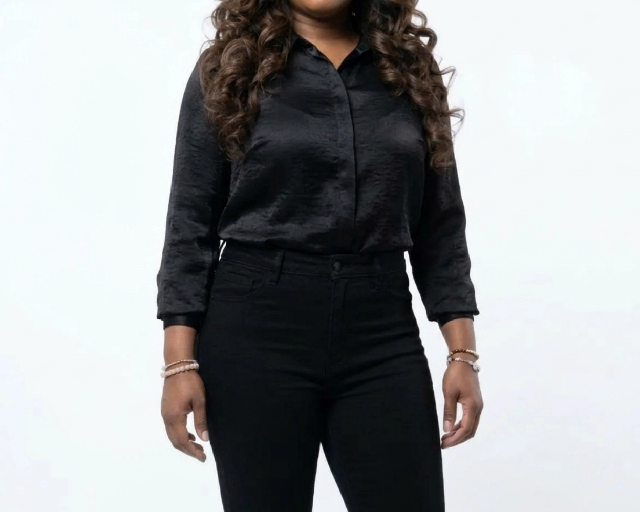 Stylish African American model wearing a chic black blouse, black high rise jeans